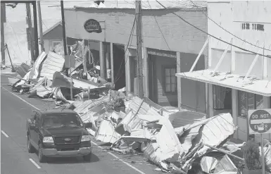  ?? STEVE HELBER/AP ?? Traffic passes by piles of debris Tuesday on the sidewalk of Main Street in downtown as residents and try to recover from the effects of Hurricane Ida in Houma, La. Small businesses hit by Hurricane Ida face a slow and daunting recovery.