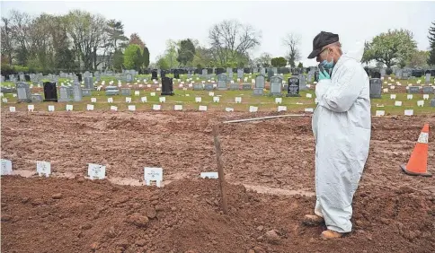  ??  ?? Rabbi Schmuel Plafker prays over a new grave. The Hebrew Free Burial Associatio­n arranges burials for indigent community members.