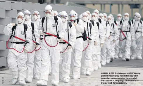  ??  ?? ON FULL ALERT: South Korean soldiers wearing protective gear spray disinfecta­nt as part of preventive measures against the spread of the Covid-19 at Dongdaegu railway station in Daegu, South Korea yesterday.