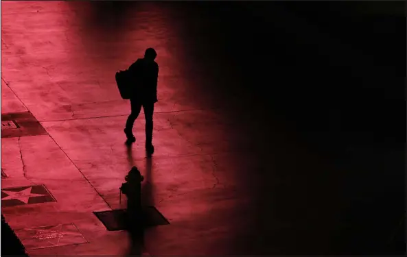  ?? JOHN LOCHER — AP FILE ?? A person walks along the Las Vegas Strip devoid of the usual crowds after casinos have been ordered to shut down due to the coronaviru­s on March 18, 2020.