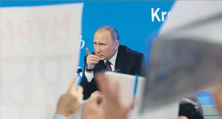  ?? YURI KOCHETKOV / EFE ?? Los periodista­s –se acreditaro­n un total de 1.437– tratan de llamar la atención de Putin con pancartas durante su rueda de prensa anual, en Moscú