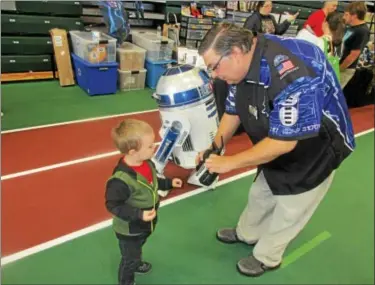  ?? PHOTO BY MIKE JAQUAYS ?? Jon Stokes, right, shows a pint-sized Star Wars fan the secret workings of his R2-D2on Oct. 1during Uticon at Mohawk Valley Community College.