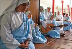  ??  ?? Nun Maria Valentina de los Angeles (center) plays the guitar as she prays alongside fellow nuns at a convent.