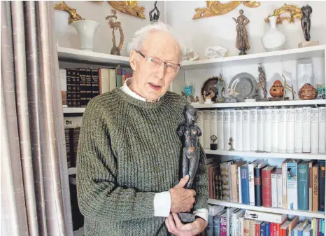  ?? FOTOS: JUNGWIRTH ?? Wolf Kalz, Künstler und Autor politische­r Schriften, vor seiner Bücherwand. In Händen hält er seine erste Plastik mit dem Titel „Hoheit“.