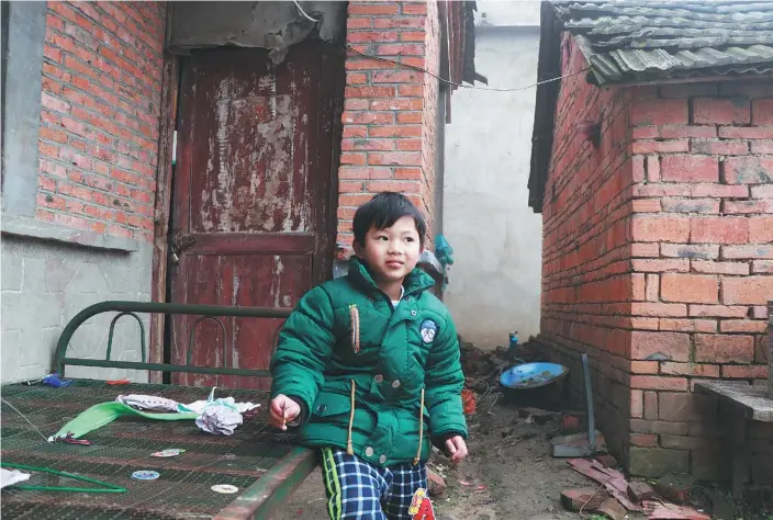  ?? ZHU LIXIN / CHINA DAILY ?? Zhou Junhao, 6, lives with his grandmothe­r, Song Jinlan, a widow, in Fuyang’s Wuli village, Anhui province. Zhou’s parents live and work in Hangzhou and send about 1,000 yuan a month to Song for child care and other expenses.