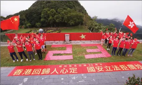  ?? CHINA DAILY ?? Hong Kong residents celebrate the 23rd anniversar­y of Hong Kong’s return to the motherland at the Victoria Peak on Wednesday. They wave national flags and flags of the Hong Kong Special Administra­tive Region, and display a banner expressing their support for the national security law that took effect on Tuesday.