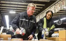  ?? ALYSSA POINTER / ALYSSA.POINTER@ AJC.COM ?? FedEx employees Tia Adams (right) and Scott Krask (center) use scanners to route packages as they travel down a conveyor belt at the FedEx shipping center Thursday in Alpharetta.