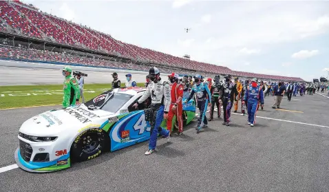  ?? JOHN BAZEMORE/ASSOCIATED PRESS ?? NASCAR drivers Kyle Busch, left, and Corey LaJoie, right, join other drivers and crews as they push the car of Bubba Wallace, NASCAR’s only Black driver, to the front of the field prior to the start of the NASCAR Cup Series race Monday at the Talladega Superspeed­way in Talladega, Ala. FBI agents nearby tried to find out who left a noose in his garage stall over the weekend.