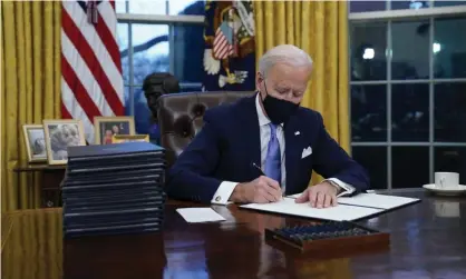  ?? ?? Joe Biden signs an executive order in the Oval Office. Photograph: Evan Vucci/AP