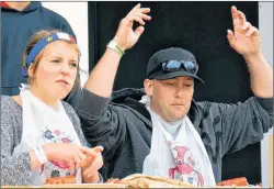  ?? DESIREE ANSTEY/ JOURNAL PIONEER ?? Robert Cassie puts his hands in the air after finishing first in the lobster eating competitio­n. Next to him, Maggie MacIsaac attempts to crack one. It was her first time eating lobster.