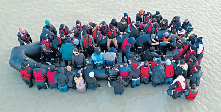  ?? ?? Migrants give a victory sign, below, as they board a boat at Gravelines and, below right, police look on as the inflatable begins its journey across the English Channel