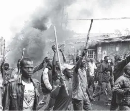  ?? THE ASSOCIATED PRESS ?? Supporters of opposition leader Raila Odinga march down a main road with rocks and sticks in the Kibera slum of Nairobi, Kenya, on Saturday. Violent demonstrat­ions have erupted in some areas after President Uhuru Kenyatta was declared victorious in the...