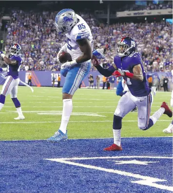  ?? AL BELLO/GETTY IMAGES ?? Detroit Lions tight end Eric Ebron scores a touchdown on a seven-yard pass under pressure from New York Giants safety Darian Thompson in the second quarter on Monday in East Rutherford, N.J.