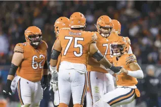  ?? ARMANDO L. SANCHEZ/CHICAGO TRIBUNE ?? Bears offensive linemen help quarterbac­k Justin Fields up after he was tackled against the Commanders on Oct. 13 at Soldier Field.