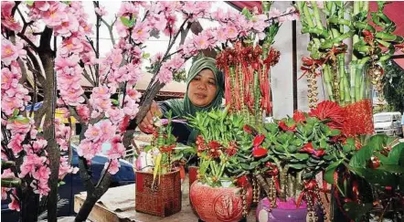  ??  ?? Business acumen: Razillah arranging Chinese New Year floral decoration­s at her stall in Johor Baru yesterday.
