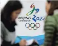  ??  ?? Personas conversan frente al logo de la candidatur­a de Beijing para los Juegos Olímpicos de Invierno 2022