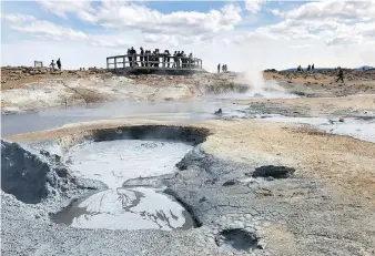  ??  ?? Visitors marvel at the steaming fumaroles and mud pots at Namafjall, a geothermal wonder.