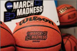  ?? The Associated Press ?? MARCH SADNESS: Official March Madness 2020 tournament basketball­s are displayed on March 16 in a storeroom at the CHI Health Center Arena in Omaha, Neb. The dominos started tumbling in March, when the NCAA abruptly called off March Madness, given no choice but to forgo a nearly $800 million TV payment that helps keep the entire college sports machine running.