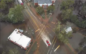  ?? Ricky Carioti Washington Post ?? A CAR travels through a flooded intersecti­on on Sunday in the town of Latta, in eastern South Carolina.