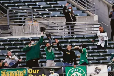  ?? Scott Strazzante / The Chronicle ?? A’s fans reach for Yan Gomes’ fourth-inning home run against the Mariners in Monday’s game at the Coliseum.