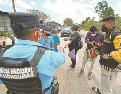  ??  ?? Policía revisa a documentos a hondureños que viajan en caravana a EU, en Corinto, Honduras