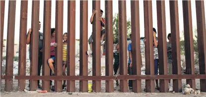  ?? PHOTOS: GETTY/ REUTERS ?? Locked out . . . Children play together on the Mexican side of the US/ Mexican border fence earlier this year. Right: Border Patrol agents form a line on motorbikes in Tucson.