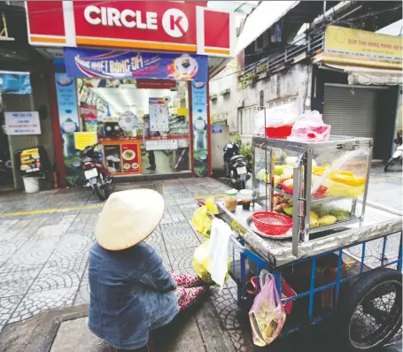  ?? MAIKE ELAN/BLOOMBERG FILES ?? A fruit vendor sits with her cart outside Circle K store, run by Couche-tard, in Ho Chi Minh City, Vietnam. If Couche-tard’s bid for Caltex Australia goes ahead, it would mark the Quebec convenienc­e store operator’s first foray into Australia, and its largest deal.