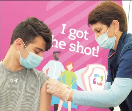  ?? Ned Gerard / Hearst Connecticu­t Media ?? Thirteen-year-old Matthew Loiz, of Shelton, gets a band aid after receiving a COVID-19 vaccinatio­n shot from nurse Mo Blees at the mass vaccinatio­n clinic on Sacred Heart University’s West Campus in Fairfield on Thursday.