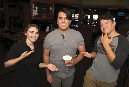  ?? VINCENT OSUNA PHOTO ?? Celia Zamora (left), an Applebee's employee and Fausto Gomez (right) pose with the sign language guesture meaning "Happy Birthday.” Carlos Alejandro Nava (middle) recently celebrated his 20th birthday at Applebee's in El Centro where servers used sign...