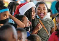  ?? Melissa Phillip / Staff photograph­er ?? Aubrenae Bailey, 8, wearing a Santa hat, and Aaliyah Wilson, 8, right, wait for a toy giveaway Thursday sponsored by the Houston Parks Department, Police Department and Greater Houston Police Activities League.