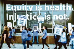  ?? Felix Uribe/Special to the Chronicle ?? Under a new law, California becomes the first state to enact a minimum wage for health industry workers, and it will likely mean a significan­t wage boost for many of them. Kaiser Permanente health care workers went on strike this month for increases similar to those covered in the new law.