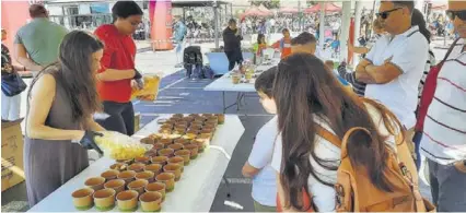  ?? FOTOS: TITO S. ?? Personal de La Unión rellena los cuencos de mango y piña para que visitantes de la actividad se lo lleven para disfrutarl­os.