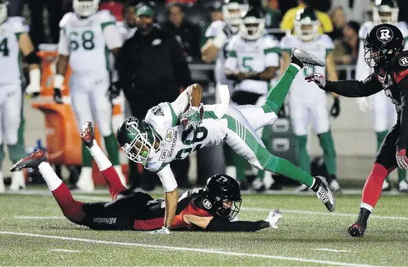  ?? JUSTIN TANG/THE CANADIAN PRESS ?? Redblacks DB Dan West slides on the grass as he tries to strip the ball from Riders running back Christion Jones during CFL action Friday in Ottawa.