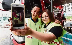  ??  ?? Selfless act: Ooi with wife Young showing a video recording of Ooi helping flood victims during their wedding day in Bukit Mertajam.