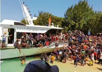  ?? Foto: Dewa Wijaya, Nusa Tenggara marine Police, dpa ?? Touristen und Einheimisc­he versuchen, einen Platz auf dem Evakuierun­gs Schiff zu ergattern, um von der Insel wegzukomme­n. Die Angst vor weiteren Beben ist groß.