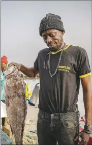  ?? ?? Fishmonger Ethio Fall holds a white grouper, the preferred fish for the dish thieboudie­nne, on May 31 at the Soumbediou­ne fish market in Dakar, Senegal.