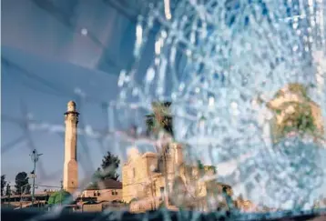  ?? DAVID GOLDMAN/AP ?? A mosque and a church are reflected in a windshield of a vehicle last month near a synagogue in Lod, Israel.