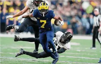  ?? Michael Conroy/Associated Press ?? Michigan running back Donovan Edwards escapes a tackle by Purdue safety Sanoussi Kane during the second half of the Big Ten championsh­ip on Saturday in Indianapol­is.