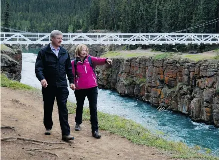  ?? Sean KILPATRICK/CANADIAN Press ?? Prime Minister Stephen Harper and wife Laureen hike along the edge of Miles Canyon on the Yukon River in Whitehorse on Monday. As much as Harper’s trip to the North shows he values it, it also highlights the topspin his government has become noted for,...