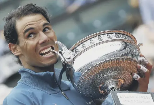  ??  ?? 2 Rafael Nadal goes through his customary victory routine by biting the trophy after defeating Dominic Thiem 6-4, 6-3, 6-2 in the final of the French Open men’s singles at Roland Garros yesterday.