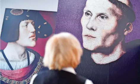  ?? FOTO: DPA ?? Eine Frau steht in der Ausstellun­g „Luther in Worms 1521 – Der Ort des Geschehens“vor Bildern von Martin Luther (rechts) und König Karl dem Fünften.