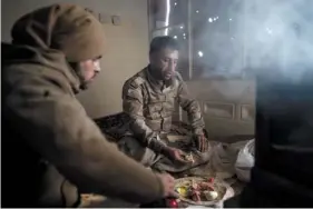  ?? AP PHOTO/FELIPE DANA ?? U.S.-backed Syrian Democratic Forces fighters eat in a building as the fight against Islamic State militants continues in the village of Baghouz, Syria, on Sunday. Islamic State militants are preventing more than 1,000 civilians from leaving a tiny area still held by the extremist group in a village in eastern Syria, a spokesman for the U.S.-backed Syrian militia fighting the group said Sunday.