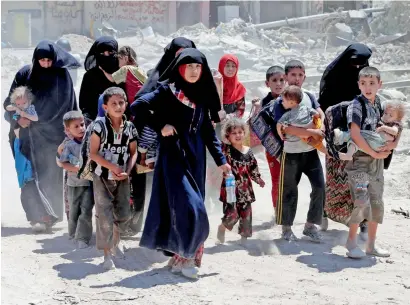  ?? Reuters ?? Displaced women and children who fled from clashes walk in the Old City of Mosul, Iraq on Saturday. —
