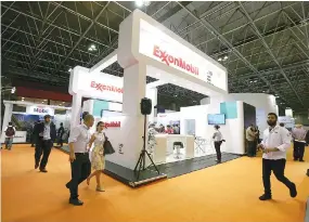  ?? REUTERS ?? PEOPLE walk near the booth of the Exxon Mobil Corp at the Rio Oil and Gas Expo and Conference in Rio de Janeiro, Brazil on Sept. 24, 2018.