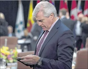  ?? THE CANADIAN PRESS/ADRIAN WYLD ?? Newfoundla­nd and Labrador Premier Dwight Ball checks his mobile device as he waits for the first ministers meeting to begin in Ottawa in a 2017 file photo.