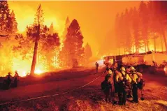  ?? NOAH BERGER/ASSOCIATED PRESS ?? The Caldor Fire crested the Sierra Nevada, forcing the unpreceden­ted evacuation this week of all 22,000 residents of South Lake Tahoe. Firefighte­rs, above, discuss strategy Thursday as the blaze consumes forest.