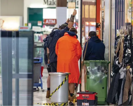  ?? Picture: Kevin Farmer ?? SMASH-AND-GRAB: Workers were called in to replace glass panes that were broken when two Brisbane girls forced their way inside the BWS bottle shop at The Ridge Shoppingwo­rld.