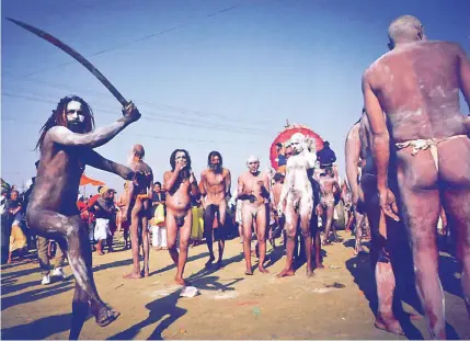  ??  ?? The ghost of armies past. A naked sadhu brandishes a sword after his ritual bath in Ganges