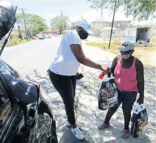  ??  ?? A member of the Kiwanis Club of St Thomas gives care packages to a resident on Friday.