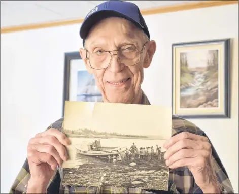  ?? KATHY JOHNSON ?? Roland DesChamp Sr. holds a photo of the first boat launched in 1963 by DesChamp and Jackson boatbuilde­rs in 1963.